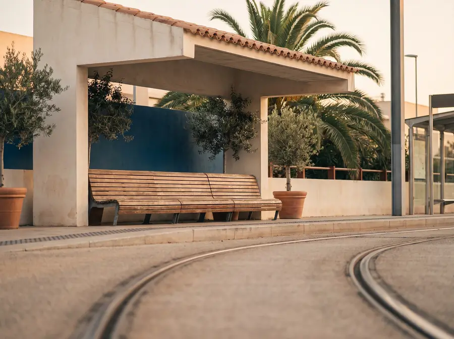An empty tram platform in evening light, rails curving out of frame